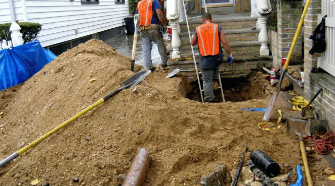 Contractors performing foundation protection and exterior drainage excavation near residential home steps in Honolulu, HI